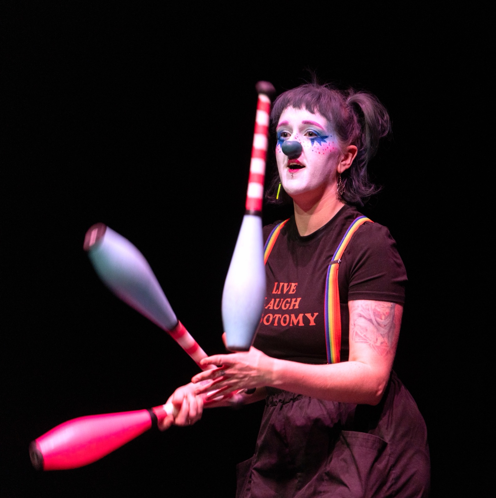 Chow juggling clubs in clown makeup on stage